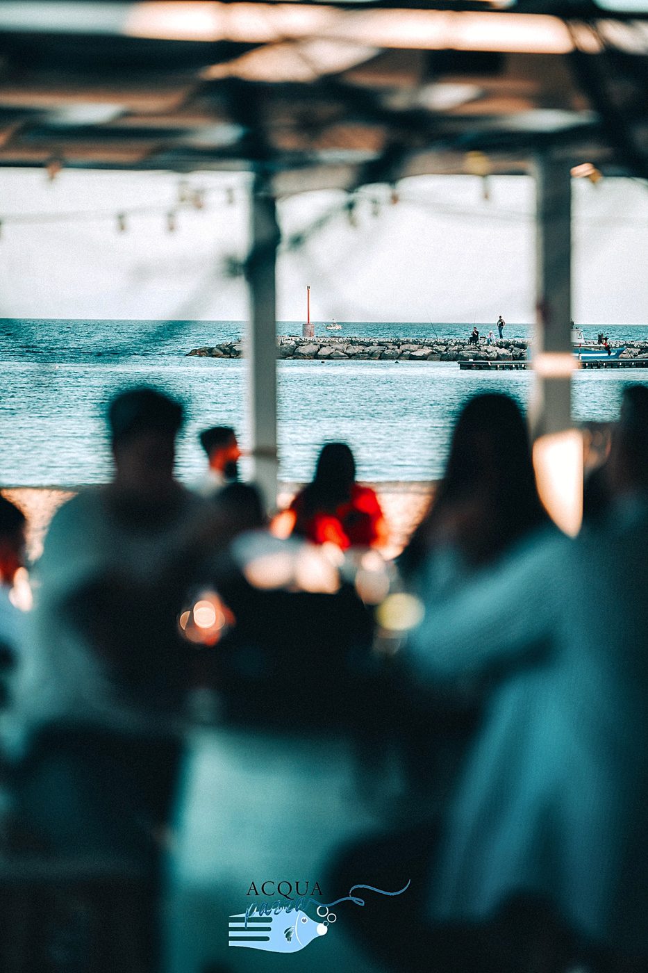 La sala di Acqua Pazza al tramonto, piena di gente, con il mare sullo sfondo